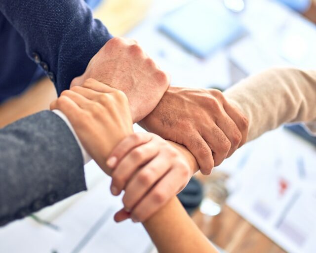 4 personnes se tenant les mains dans un contexte professionnel